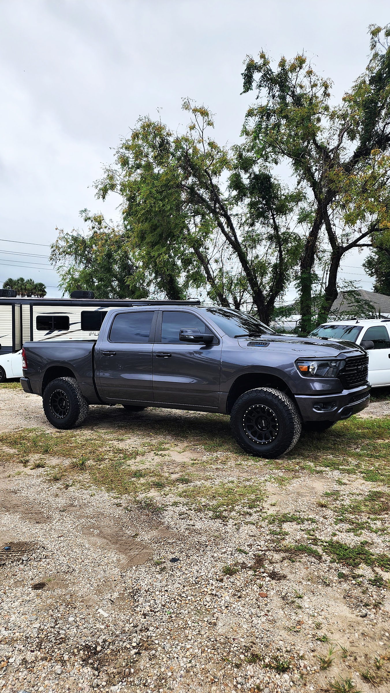Gray RAM 1500 on black wheels and all-terrain tires, parked on the lot with RVs behind