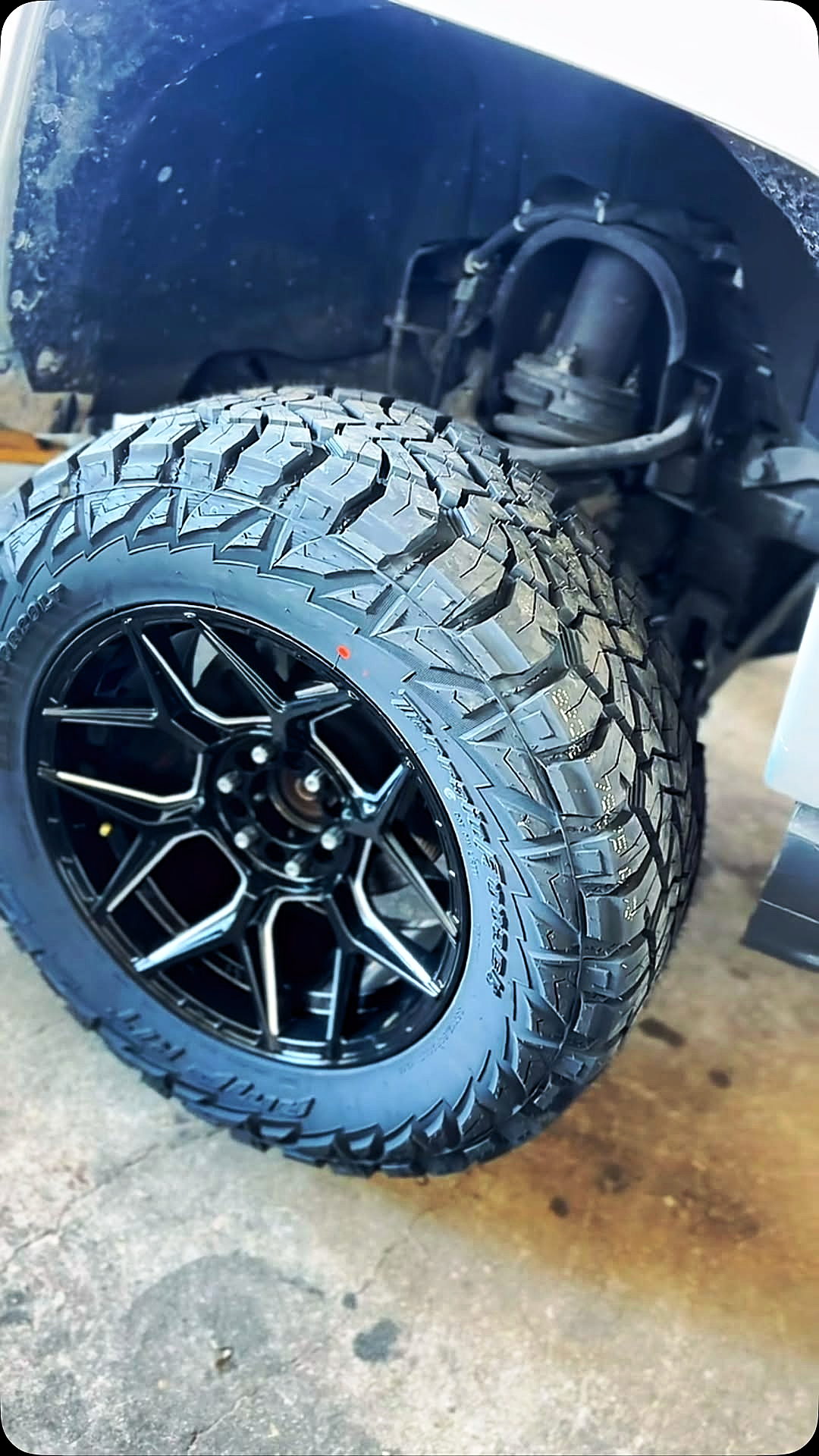 Black machined wheel and mud-terrain tire fitted under a truck fender, suspension visible (Instagram reel cover)